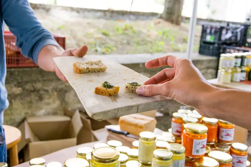 marche-de-producteurs-Montcuq Sur le marché à Montcuq, un producteur fait goûter son produit à un potentiel acheteur.