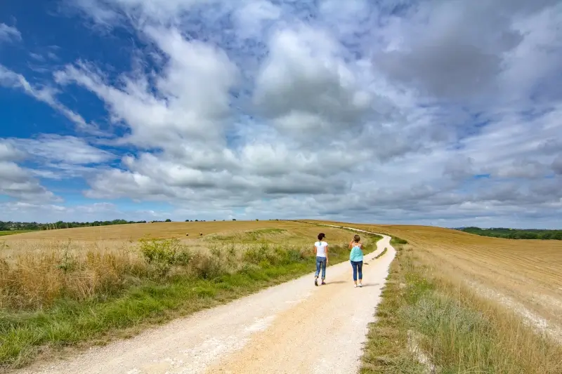 hiking-in-quercy-blanc Two women walking along a white limestone path, surrounded by fields, in Quercy Blanc.