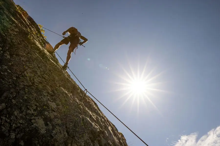 Un homme en train de faire de l'escalade en extérieur, sur une falaise. 