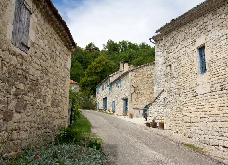 Une ruelle dans le petit village de Sainte-Croix, avec ses maisons en pierre blanche aux volets bleu ciel, typiques du Quercy Blanc.
